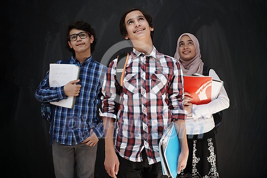 Arabic teenagers, students group  portrait against black chalkboard wearing backpack and books in school