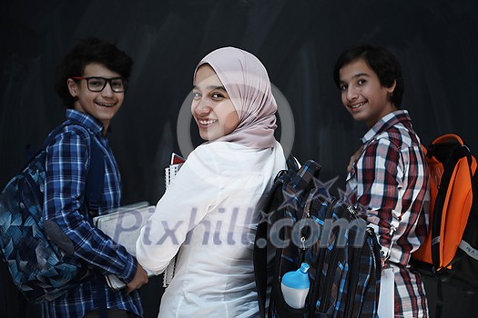 Arabic teenagers, students group  portrait against black chalkboard wearing backpack and books in school