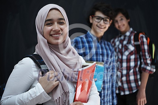 Arabic teenagers, students group portrait against black chalkboard wearing backpack and books in school Arabic teenagers, students group portrait against black chalkboard wearing backpack and books in school