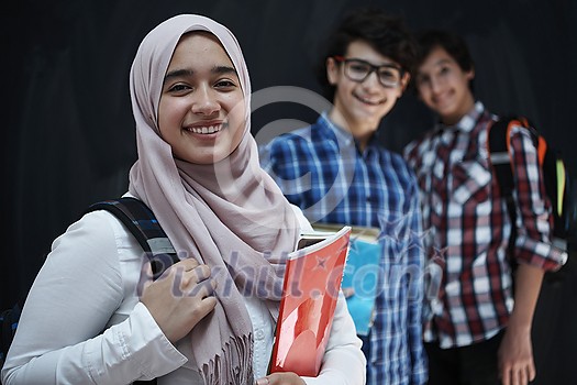 Arabic teenagers, students group  portrait against black chalkboard wearing backpack and books in school