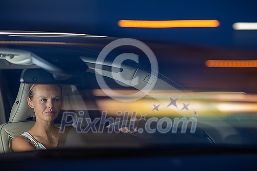 Young female driver driving her car at night (color toned image; shallow DOF)