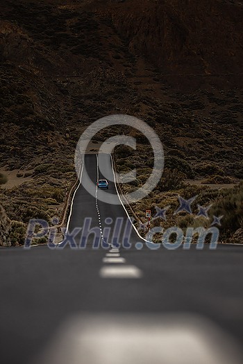 Long road in a mountain valley with a car on it - Teide National Park, Tenerife, Canary islands Long road in a mountain valley with a car on it - Teide National Park, Tenerife, Canary islands