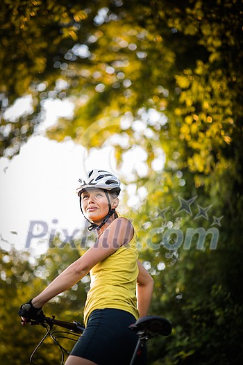 Pretty, young woman biking on a mountain bike enjoying healthy active lifestyle outdoors in summer (shallow DOF) Pretty, young woman biking on a mountain bike enjoying healthy active lifestyle outdoors in summer (shallow DOF)