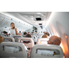 Pretty, young woman aboard an airplane during a lang haul commercial flight - stretching her legs a bit, walking in the aisle