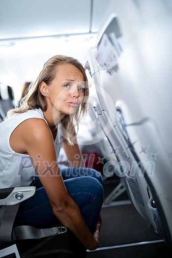 Young happy woman aboard an airplane during flight  - not feeling quite well