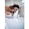 Pretty, middle aged woman brushing her teeth in a modern design bathroom