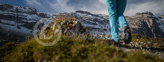 Pretty, young female hiker walking in high mountains (shallow DOF)