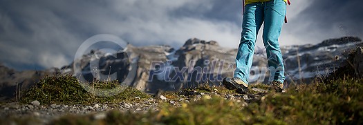 Pretty, young female hiker walking in high mountains (shallow DOF)