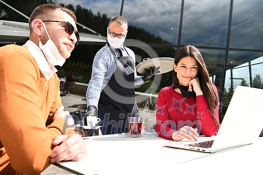 coronavirus outbreak Group of casual business People in outdoor restaurant wearing protective medical mask, business team collaborating and brainstorming business ideas while working on laptop coronavirus outbreak Group of casual business People in outdoor restaurant wearing protective medical mask, business team collaborating and brainstorming business ideas while working on laptop