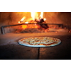 Rustic pizza is removing from hot stove where it was baked. Cook using special shovel to removing them. This restaurant have special wood fired oven
