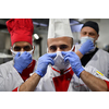 Mixed race team Portrait of group chefs standing together in the kitchen at restaurant wearing protective medical mask and gloves in coronavirus new normal concept