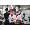 Mixed race team Portrait of group chefs standing together in the kitchen at restaurant wearing protective medical mask and gloves in coronavirus new normal concept