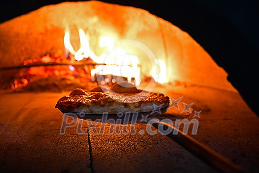 Rustic pizza is removing from hot stove where it was baked. Cook using special shovel to removing them. This restaurant have special wood fired oven Rustic pizza is removing from hot stove where it was baked. Cook using special shovel to removing them. This restaurant have special wood fired oven