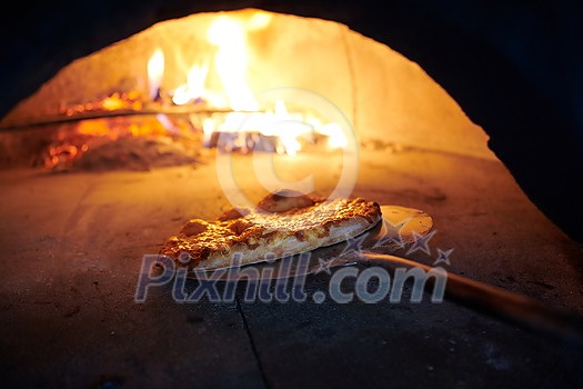 Rustic pizza is removing from hot stove where it was baked. Cook using special shovel to removing them. This restaurant have special wood fired oven Rustic pizza is removing from hot stove where it was baked. Cook using special shovel to removing them. This restaurant have special wood fired oven