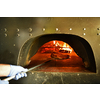 Skilled chef preparing traditional italian pizza  in interior of modern restaurant kitchen with special wood-fired oven. Wearing protective medical face mask and gloves in coronavirus new normal concept