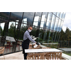 Waiter cleaning the table with Disinfectant Spray in a restaurant wearing protective medical mask and gloves new normal concept