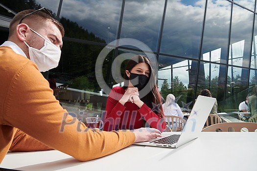 coronavirus outbreak Group of casual business People in outdoor restaurant wearing protective medical mask, business team collaborating and brainstorming business ideas  while working on laptop