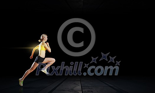 Young woman athlete running fast on dark background Young woman athlete running fast on dark background