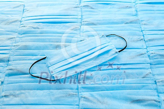 Antibacterial medical protective blue face mask on the same color background from masks. Concept of prevention from respiratory sickness and viruses.