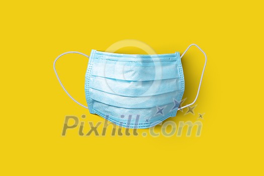 Textile medical antibacterial protective blue face mask on a yellow background, copy space. Concept of prevention from respiratory sickness and viruses.