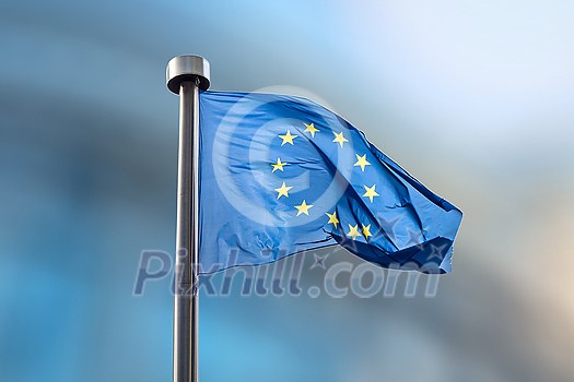 Waving flag of European Union on a blurred backgroud of parliament in Brussels, Belgium with copy space.