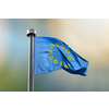 Flag of European Union with round from molecules of Coronavirus instead of stars on a blurred backgroud of parliament in Brussels, Belgium with copy space. Quarantine concept.