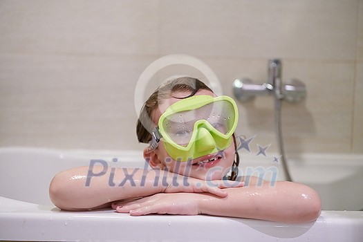 little girl with snorkel goggles in the tub while taking a bath in the bathtub, kids hygiene concept and summer vacation in corona virus stay at home