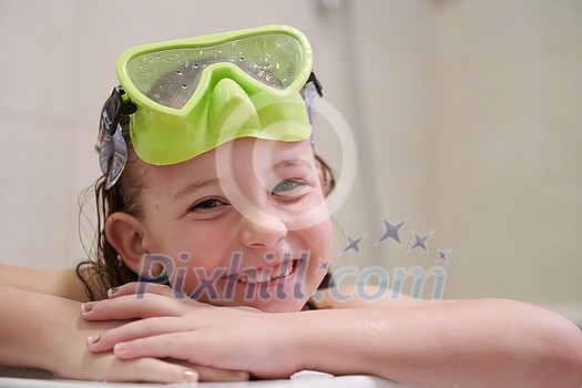 little girl with snorkel goggles in the tub while taking a bath in the bathtub, kids hygiene concept and summer vacation in corona virus stay at home