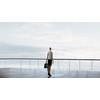 Back view of businesswoman standing on roof looking at city