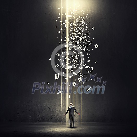 Businessman with hands spread apart standing in light coming from above Businessman with hands spread apart standing in light coming from above