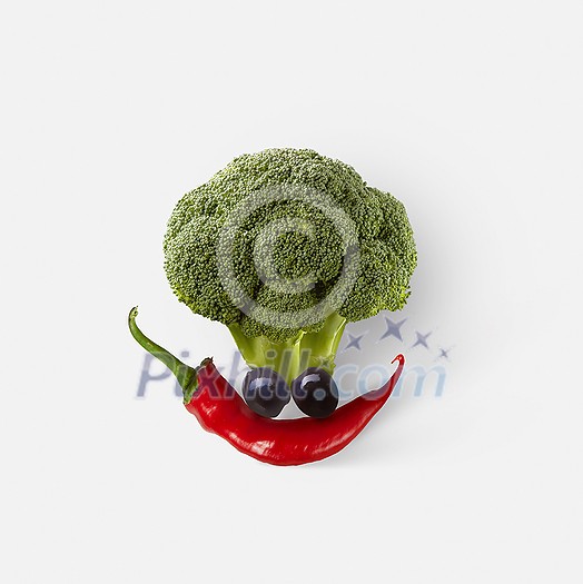 Creative composition in the shape of funny face made from freshly picked natural organic vegetables on a white background, copy space. Vegan healthy food concept.