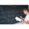 Handsome college student solving a math problem during math class in front of the blackboard/chalkboard (color toned image)