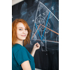 Portrait of a pretty young college student writing on the blackboard during a maths class (color toned image)