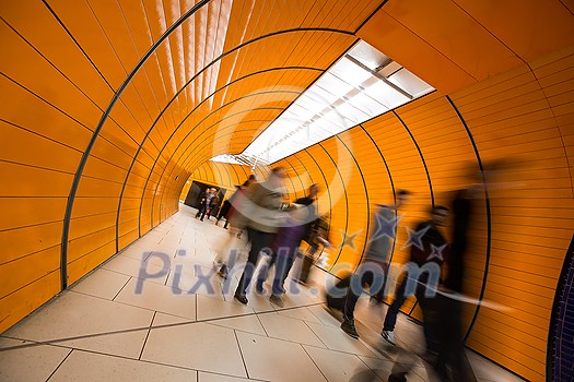People rushing through a subway corridor (motion blur technique is used to convey movement)