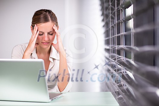 Pretty female manager/office clerk/lawyer in a modern office, holding a tablet  computer, looking at the camera, smiling, looking confident