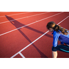 Pretty female runner stretching before her run at a track and field stadium