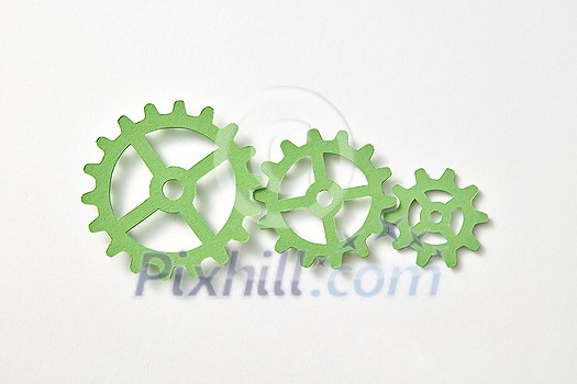 Set of papercraft machine gear different size handmade from green color paper on a white background with shadows, copy space. Top view. Set of papercraft machine gear different size handmade from green color paper on a white background with shadows, copy space. Top view.
