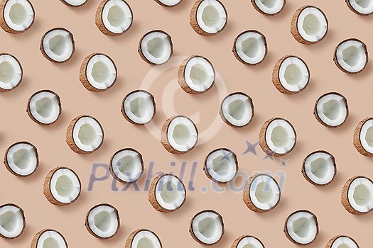 Creative fruits pattern from natural organic tropical coconut's halves on a beige background. Flat lay. Vegan concept.
