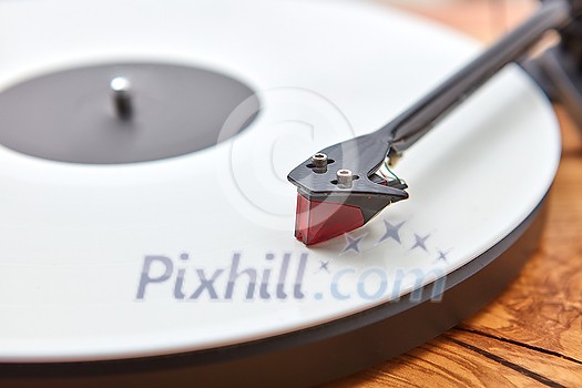 Vintage old-fashioned turnable record player with retro vinil disc on a wooden table, copy space. Close up view. Popular disco trends 60s, 70s, 80s, 90s. Vintage old-fashioned turnable record player with retro vinil disc on a wooden table, copy space. Close up view. Popular disco trends 60s, 70s, 80s, 90s.