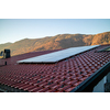 Alternative energy solar panels on a tiled roof on a background of stone mountains and clear blue sky in autumn day, Austria.