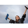 Pretty, young woman celebrating joyfully her graduation - spreading wide her arms, holding her diploma, savouring her success (color toned image; shallow DOF)