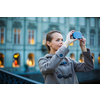 Elegant, young woman taking a photo with her cell phone camera while traveling (shallow DOF; color toned image)