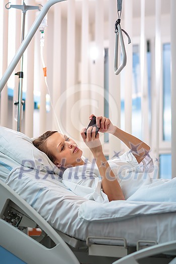 Pretty, young, female patient in a modern hospital room. Getting better fast after a surgery - pensive yet positive, thinking ahead, making plans (shallow DOF; color toned image) Pretty, young, female patient in a modern hospital room. Getting better fast after a surgery - pensive yet positive, thinking ahead, making plans (shallow DOF; color toned image)