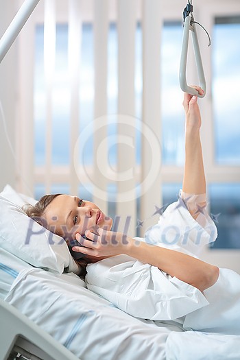 Pretty, young, female patient in a modern hospital room. Getting better fast after a surgery - pensive yet positive, thinking ahead, making plans (shallow DOF; color toned image) Pretty, young, female patient in a modern hospital room. Getting better fast after a surgery - pensive yet positive, thinking ahead, making plans (shallow DOF; color toned image)