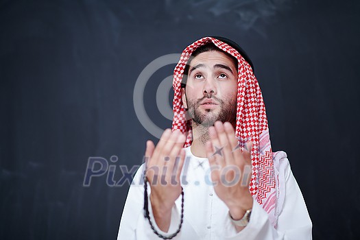 young arabian man in traditional clothes making traditional prayer to God, keeps hands in praying gesture in front of black chalkboard representing modern islam fashion and ramadan kareem concept young arabian man in traditional clothes making traditional prayer to God, keeps hands in praying gesture in front of black chalkboard representing modern islam fashion and ramadan kareem concept