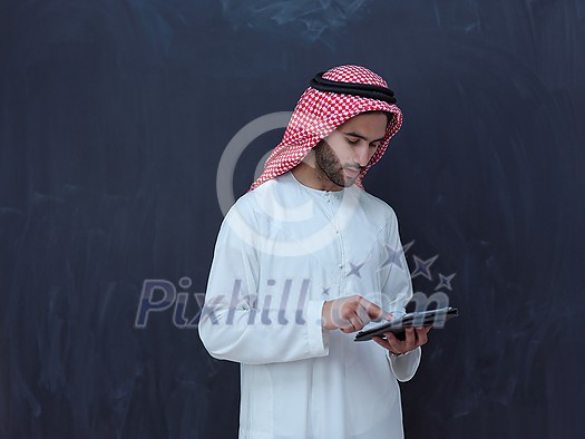 young arabian muslim businessman using tablet computer wearing hijab clothes in front of black chalkboard young arabian muslim businessman using tablet computer wearing hijab clothes in front of black chalkboard