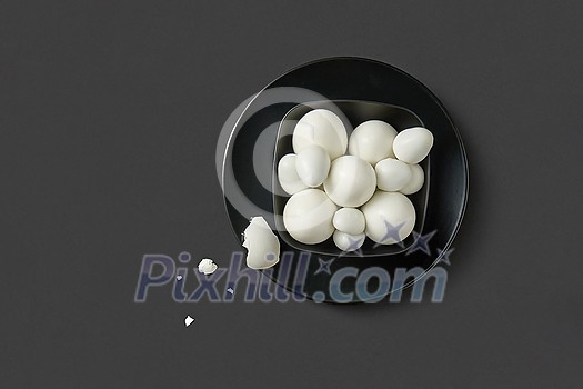 Freshly boiled natural farm chicken and quail eggs on a black plate for preparing healthy meal on a dark grey background, copy space. Top view. Healthy natural food. Freshly boiled natural farm chicken and quail eggs on a black plate for preparing healthy meal on a dark grey background, copy space. Top view. Healthy natural food.