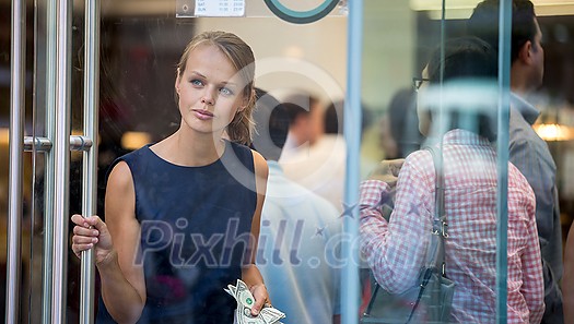 Pretty, young woman leaving a store/restaurant with cash in her hand after having paid for for the goods/food Pretty, young woman leaving a store/restaurant with cash in her hand after having paid for for the goods/food