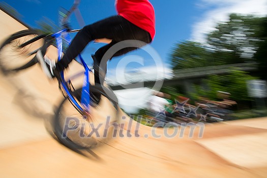 Bmx rider jumping over on a U ramp in a skatepark (motion blurred image)