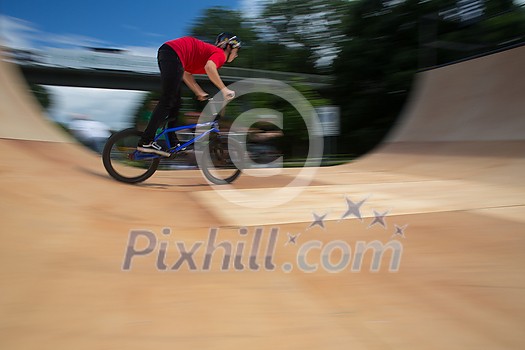 Bmx rider jumping over on a U ramp in a skatepark (motion blurred image)